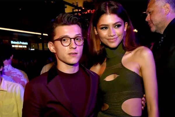 Tom Holland smiling at a red carpet event showcasing his height and style.